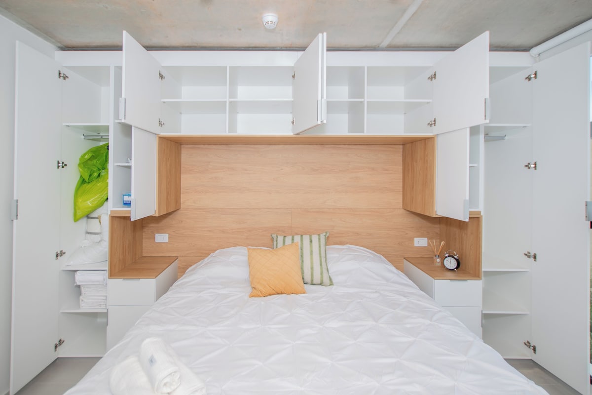 A bedroom with a bed, built-in shelving, and a view of the outside.