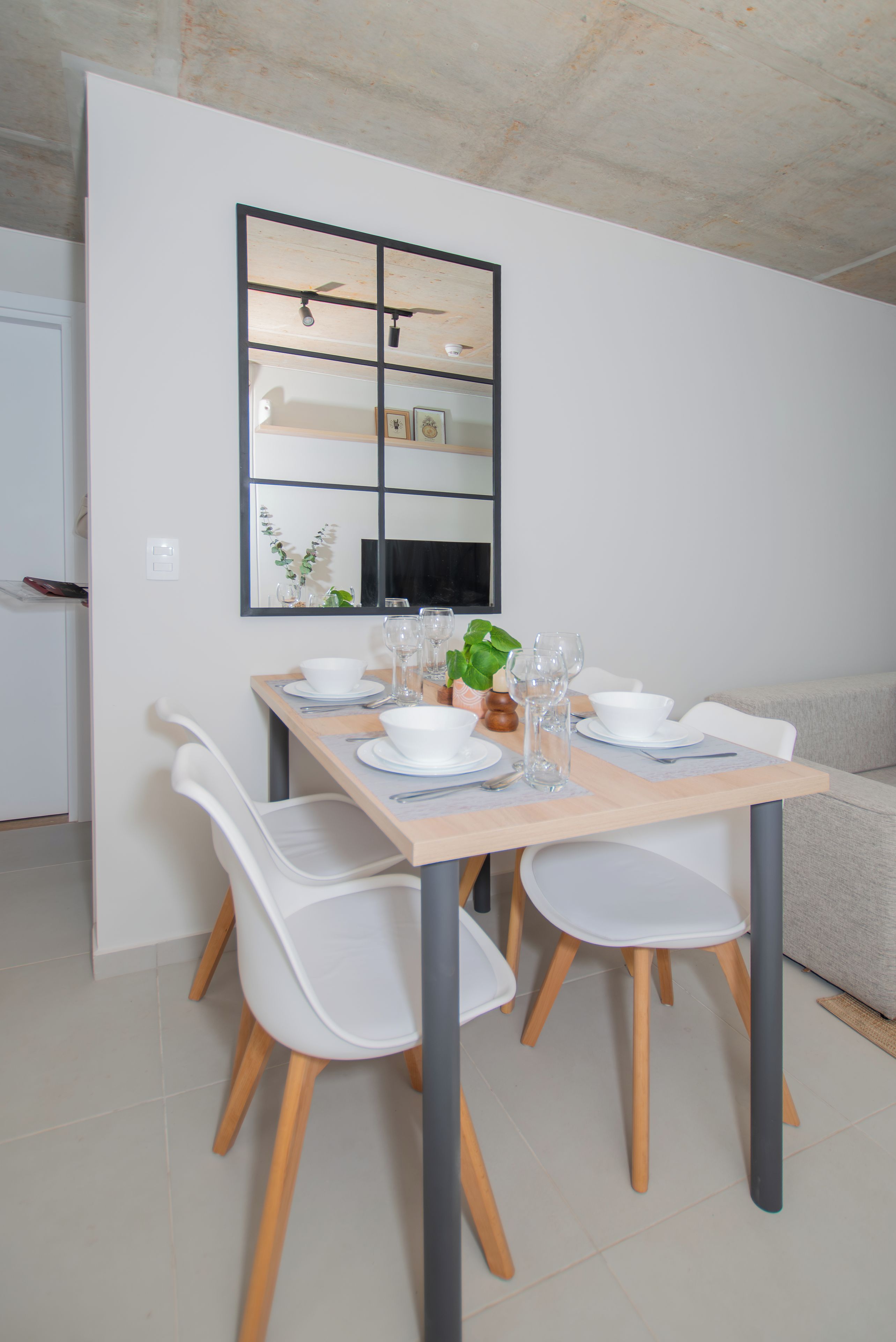 A dining area with a table set for four, white chairs, and a modern ceiling fan.