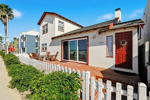Ein Strandgrundstück mit weißer Fassade, einer roten Tür und der Hausnummer 3345.
