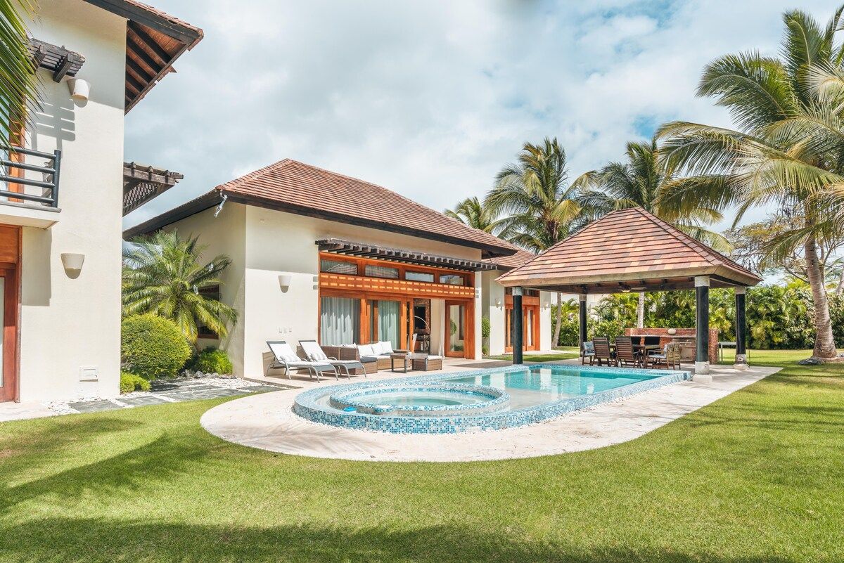 A modern two-story house with a swimming pool, a covered patio, and a well-maintained lawn.