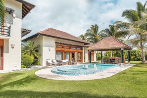 Una casa moderna de dos pisos con piscina, un patio cubierto y un césped bien cuidado.