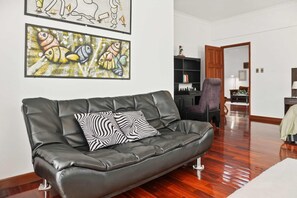 A living room with a black leather sofa, two zebra-patterned cushions, and two abstract fish paintings on the wall. - Luxury penthouse with rooftop, sauna, jacuzzis and city views (Cochabamba)