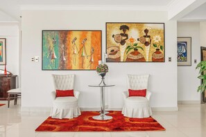 A room with two white armchairs, a red rug, and two paintings on the wall. - Luxury penthouse with rooftop, sauna, jacuzzis and city views (Cochabamba)