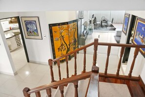 A staircase with wooden railings leading to a dining area with a glass partition and artwork on the walls. - Luxury penthouse with rooftop, sauna, jacuzzis and city views (Cochabamba)