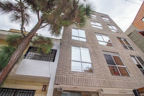 A multi-story building with a brick facade, large windows, and a palm tree in front. - 51 Close to Laureles, Metro and Restaurants (Medellín)