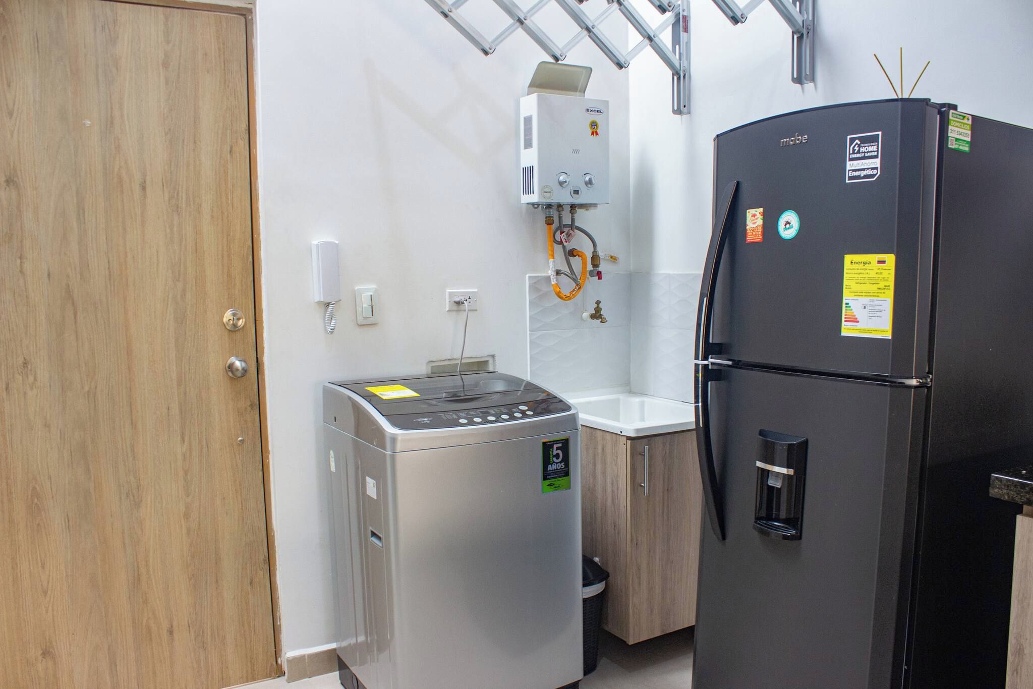 Una cocina compacta equipada con refrigerador, lavadora y calentador de agua.