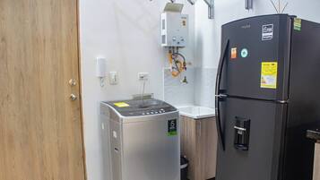 Una cocina compacta equipada con refrigerador, lavadora y calentador de agua.