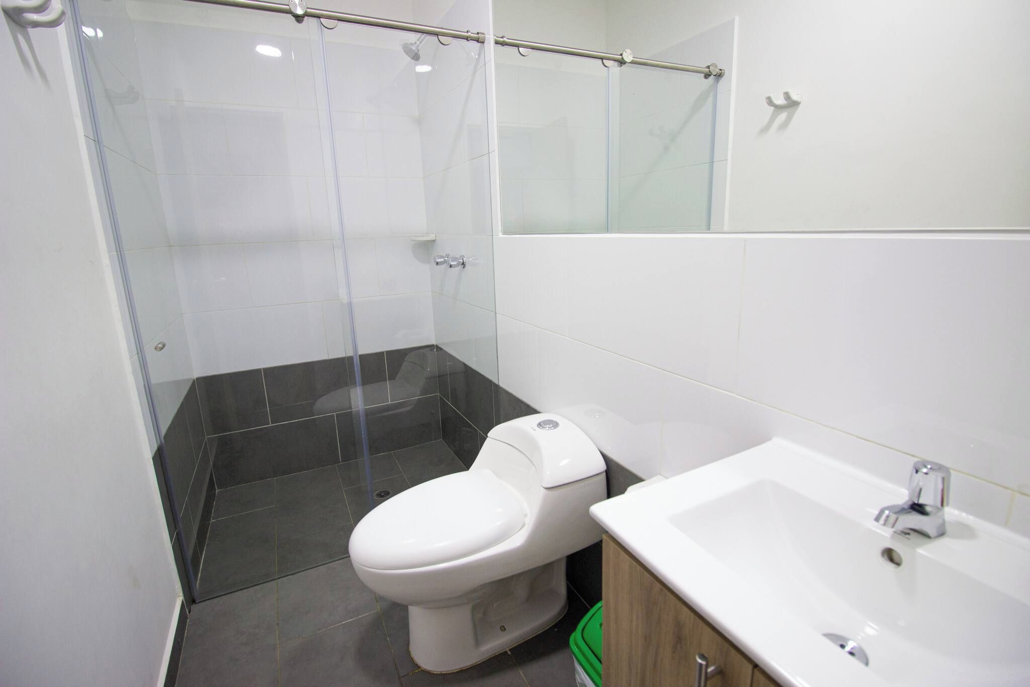 A modern bathroom with a toilet, a shower enclosure, and a sink.