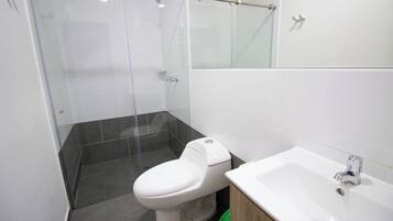 A modern bathroom with a toilet, a shower enclosure, and a sink.