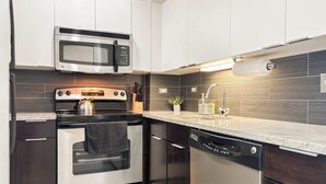 A modern kitchen with stainless steel appliances, a microwave, oven, and dishwasher. - Compact Studio for a Relaxed Stay (Chicago)