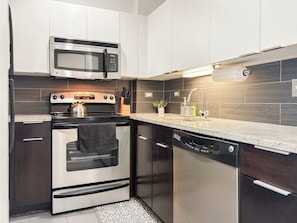 Een moderne keuken met roestvrijstalen apparatuur, een magnetron, oven en vaatwasser.