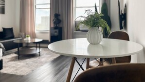 A modern living room with a round white table, a potted fern, and a sofa. - Compact Studio for a Relaxed Stay (Chicago)