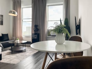 Een moderne woonkamer met een ronde witte tafel, een potplant varens en een bank.