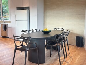 A modern kitchen with a built-in refrigerator, a dining table with chairs, and a speaker. - Sopris Mountain Retreat w/ Pool & Mountain Views (Carbondale)
