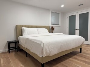 A bedroom with a bed, a nightstand, a window with blinds, and a door. - Sopris Mountain Retreat w/ Pool & Mountain Views (Carbondale)