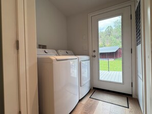 A laundry room with two front-loading washers and dryers, a door leading outside, and a wooden floor. - Sopris Mountain Retreat w/ Pool & Mountain Views (Carbondale)