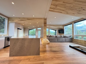 A spacious living area with a large wooden ceiling, a central island, and a seating area with a sofa and cushions. - Sopris Mountain Retreat w/ Pool & Mountain Views (Carbondale)
