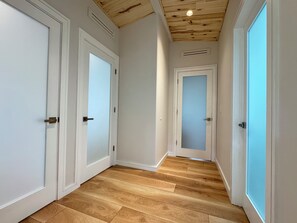 A hallway with wooden flooring, white walls, and doors with frosted glass panels. - Sopris Mountain Retreat w/ Pool & Mountain Views (Carbondale)