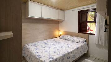 A small bedroom with a single bed, a nightstand, a window with a view of a bicycle, and a wooden ceiling.