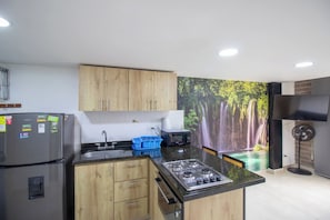 Una cocina moderna con armarios de madera, estufa a gas, microondas y pileta.