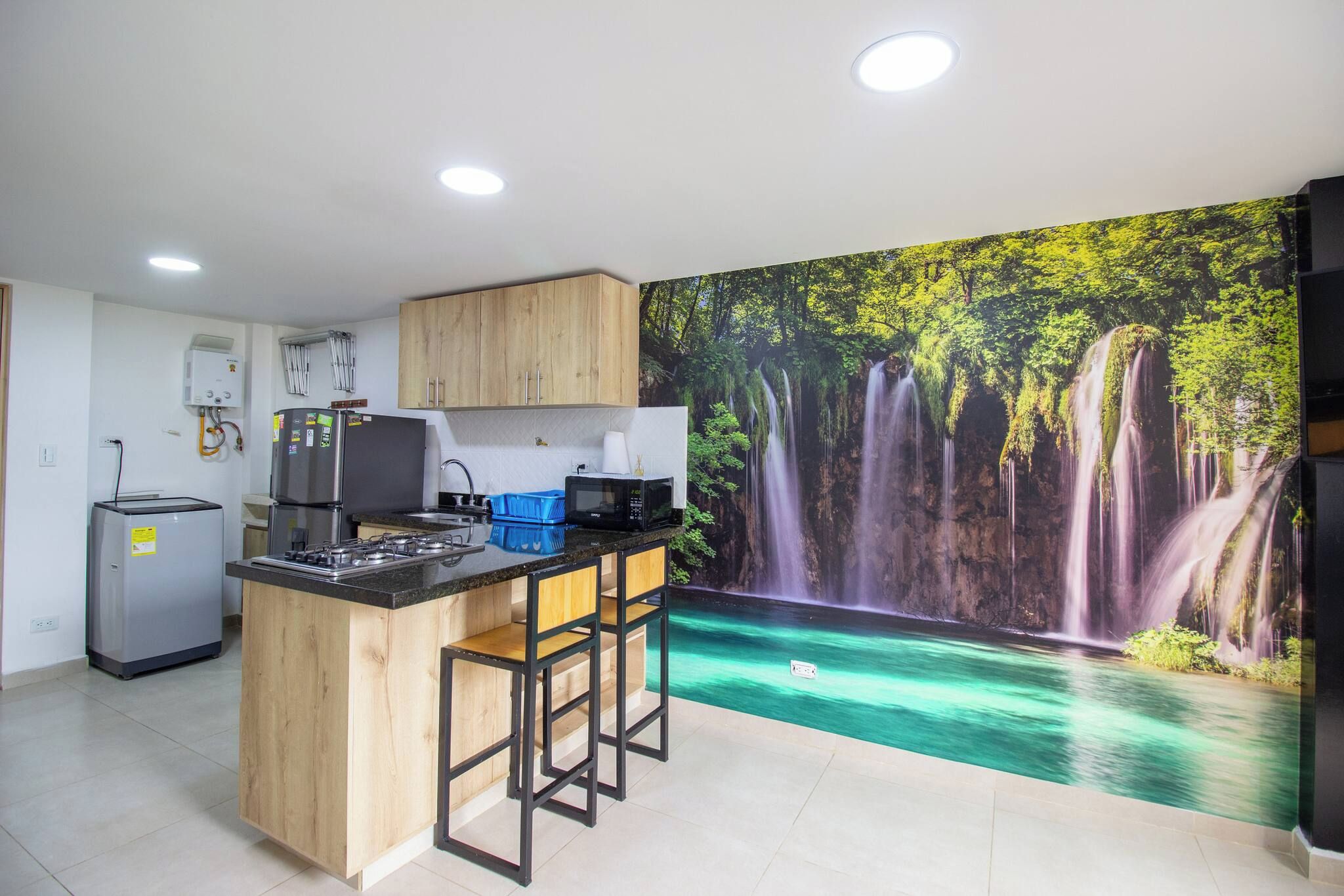 Una cocina con una isla central, un refrigerador, un microondas y un calentador de agua.