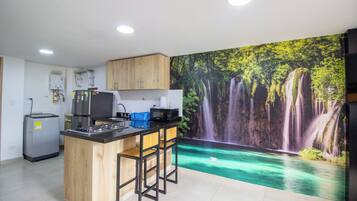 Una cocina con una isla central, un refrigerador, un microondas y un calentador de agua.