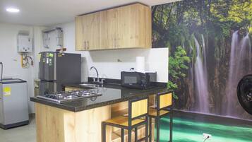 A kitchen with wooden cabinets, a gas stove, a refrigerator, a microwave, and a sink.