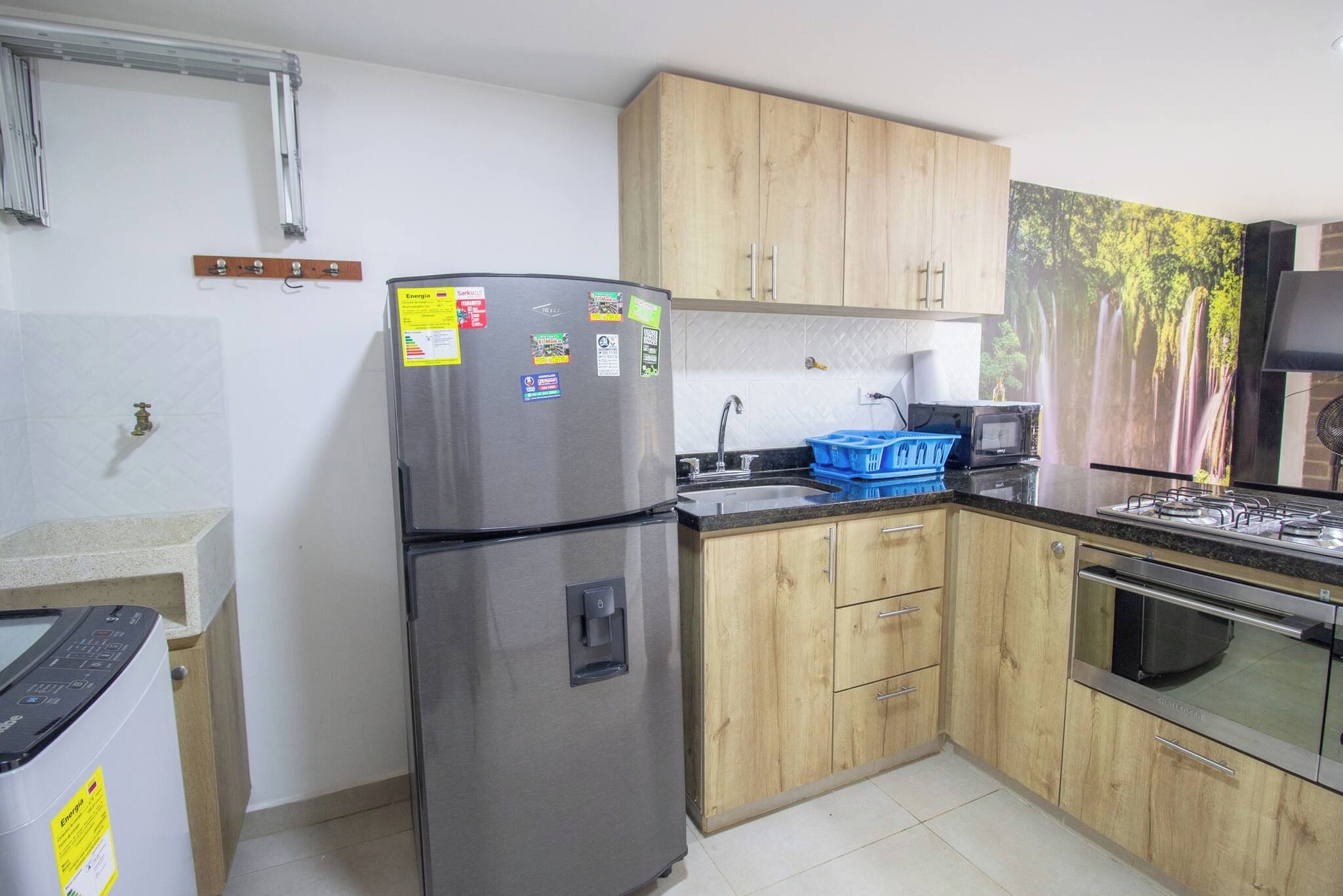 Una cocina con un refrigerador de acero inoxidable, armarios de madera, un microondas y una estufa.
