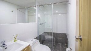 Um banheiro moderno com chuveiro em box de vidro, pia branca e vaso sanitário.