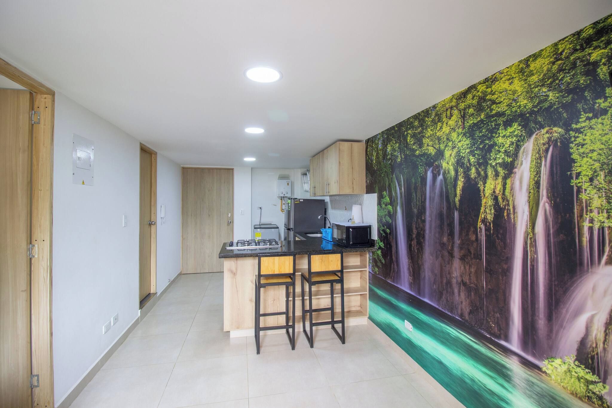 Una cocina moderna con una isla central, armarios de madera y un mural estilo cascada en la pared.