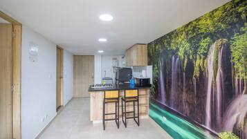 Una cocina moderna con una isla central, armarios de madera y un mural estilo cascada en la pared.