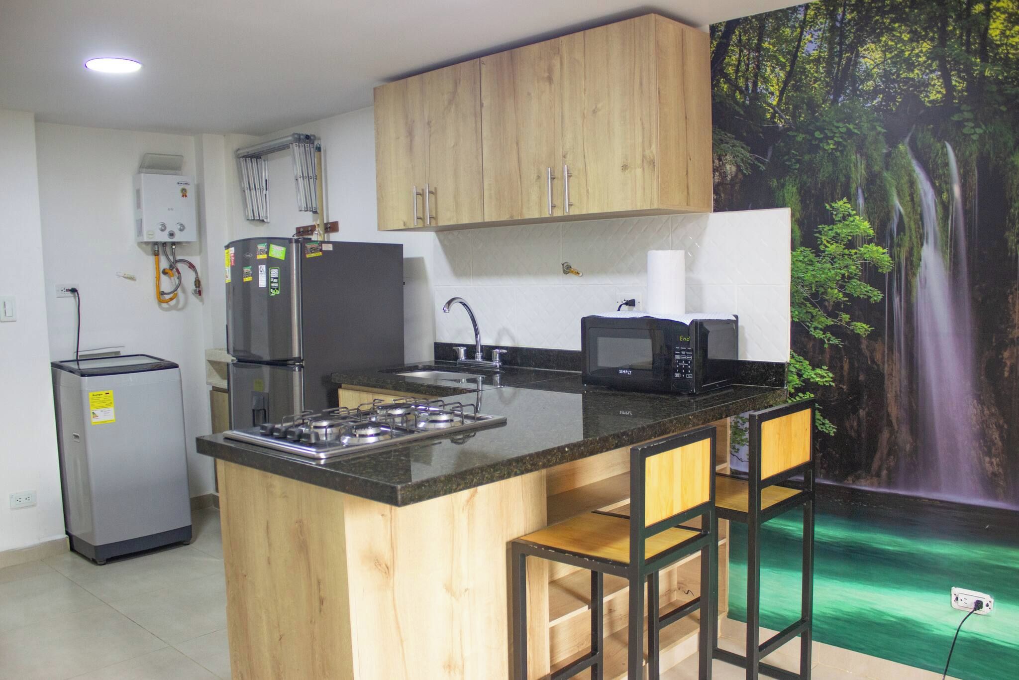 Una cocina con una isla central, un refrigerador, un microondas y un lavamanos.