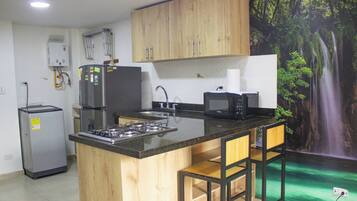 Una cocina con una isla central, un refrigerador, un microondas y un lavamanos.