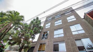 A multi-story building with a brick facade, large windows, and a visible balcony on the second floor.