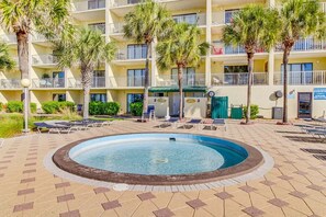 A hotel with a swimming pool surrounded by lounge chairs and palm trees. - The Summit 325 (Panama City Beach)