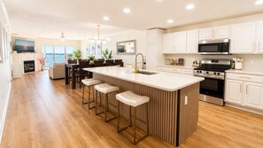 A modern kitchen with a large island, bar stools, white cabinetry, and stainless steel appliances. - 3BR Bayfront | Boardwalk |Sunsets Balcony |Pool | Parking (Ocean City)