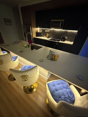 Een moderne keuken met een centraal eiland, witte kasten en een magnetron.