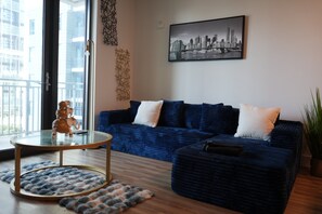 A modern living room with a blue sofa, a glass coffee table, and a cityscape painting on the wall. - The Royal Suite luxury apartment Downtown Atlanta Views (Atlanta)