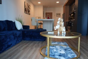 A modern living room with a blue sofa, a glass coffee table, and a decorative elephant figurine. - The Royal Suite luxury apartment Downtown Atlanta Views (Atlanta)