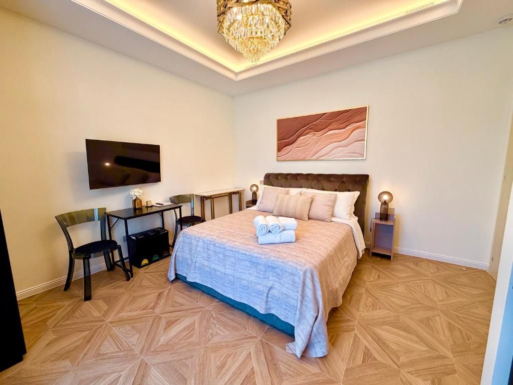 Een hotelkamer met een bed, een bureau, een stoel, een televisie en een kroonluchter.