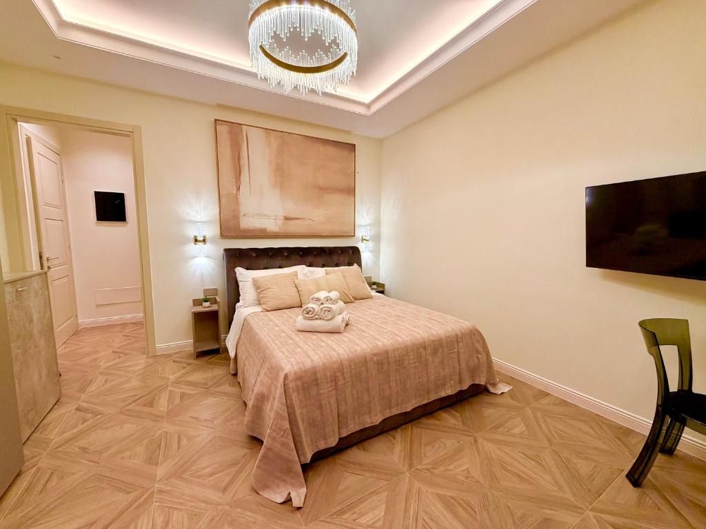 A bedroom with a bed, a television, a chandelier, and a door.
