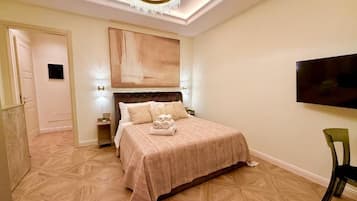 A bedroom with a bed, a television, a chandelier, and a door.