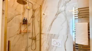 A modern bathroom with a glass-enclosed shower, marble walls, and a white toilet.