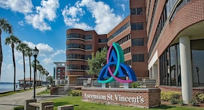 A building with a prominent logo, a sign reading 'Ascension St. Vincent's,' and a waterfront view. - Mins 2 Everbank - Baptist UF - Health - Beach - Airport (Jacksonville)