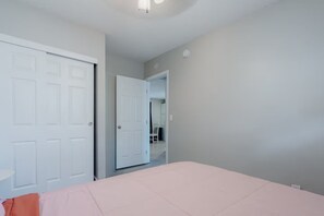 A bedroom with a bed, a door, and a hallway leading to a bathroom. - Mins 2 Everbank - Baptist UF - Health - Beach - Airport (Jacksonville)