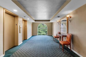 A hallway with a patterned carpet, a large arched window, and a mirror with wall sconces. - Aventura Palm Retreat - 2BR Pool Gym Tennis (Aventura)