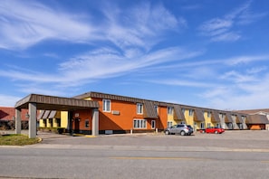 A motel with a covered parking area and multiple-story buildings.