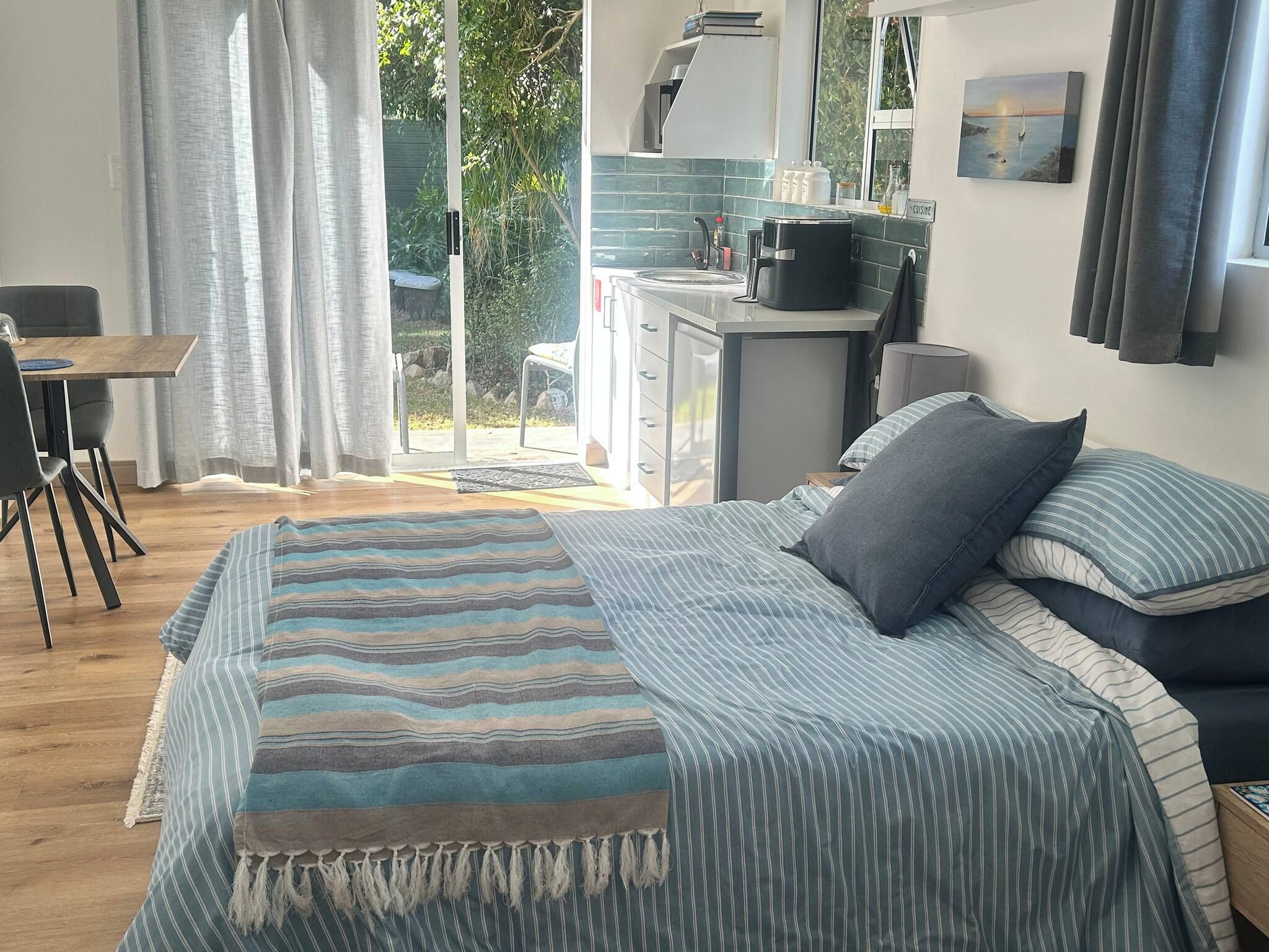 A bedroom with a bed, a desk, and a view of the outdoors.