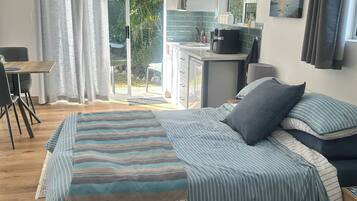 A bedroom with a bed, a desk, and a view of the outdoors.