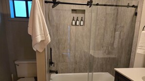 Ett badrum med toalett, badkar och en duschavdelning med glasväggar.